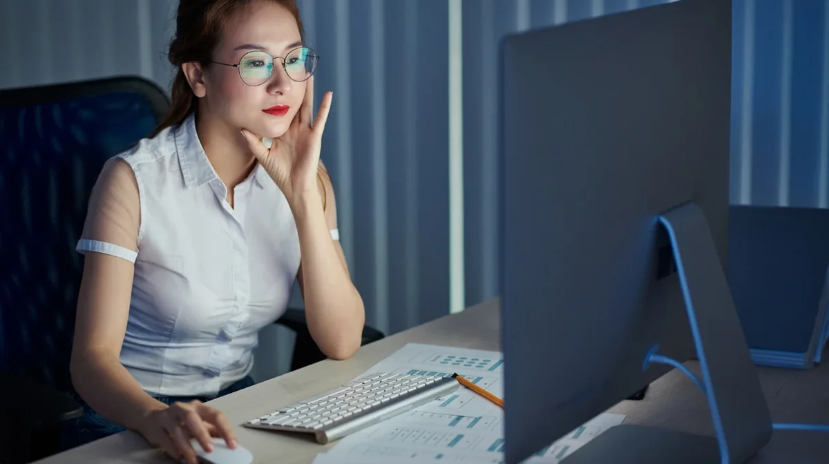 A professional reviewing work at a desktop monitor