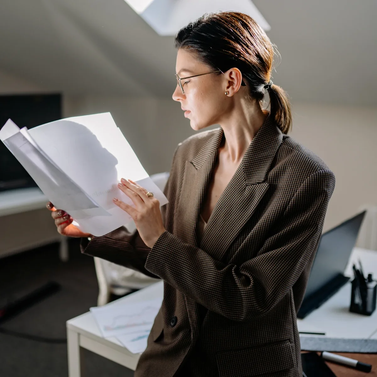 A professional reviewing printed documents beside a computer