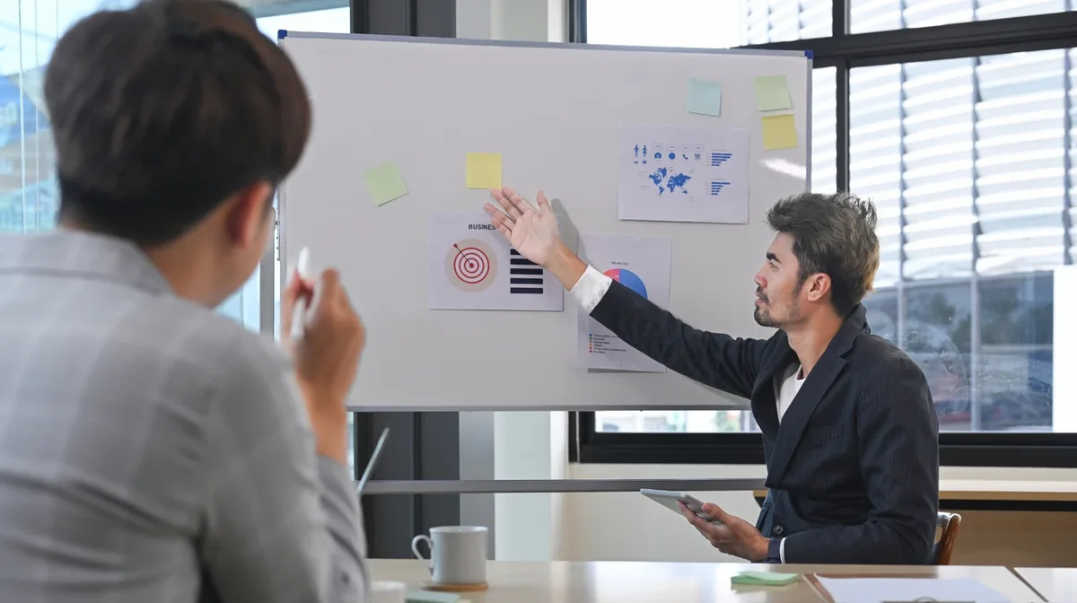 A presenter explaining a diagram on a whiteboard