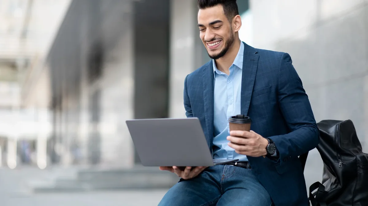 A professional using a laptop while standing outside an office