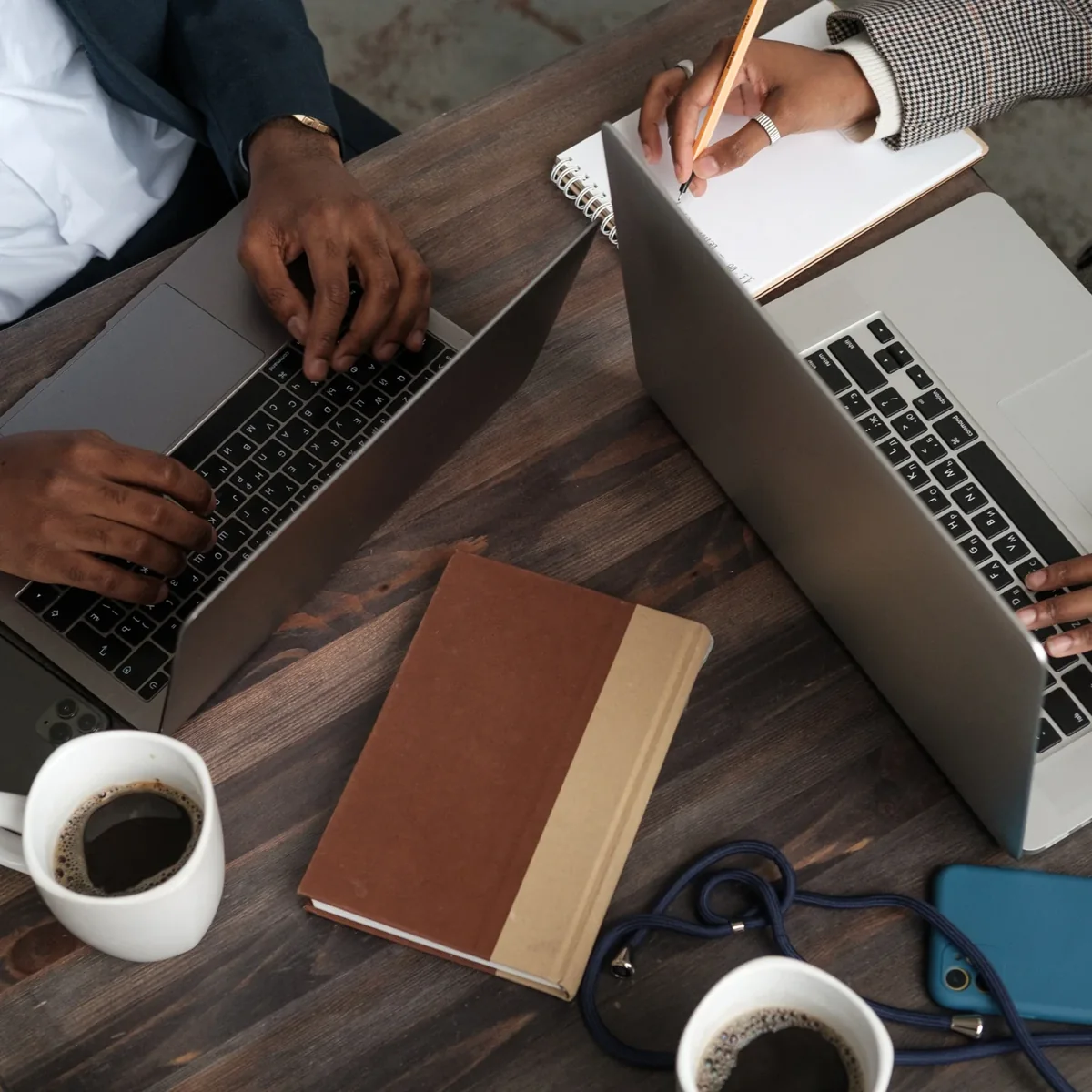 A workspace with a notebook, laptop, and coffee