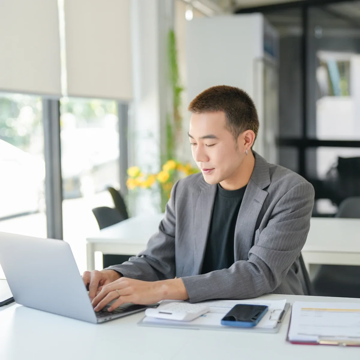 A learner concentrating on a laptop beside a window