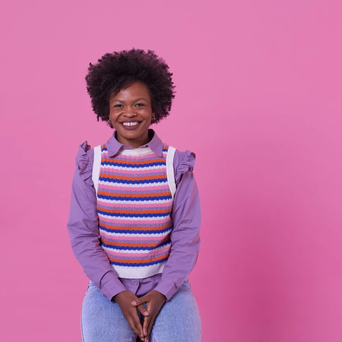A smiling student with a backpack against a pink background